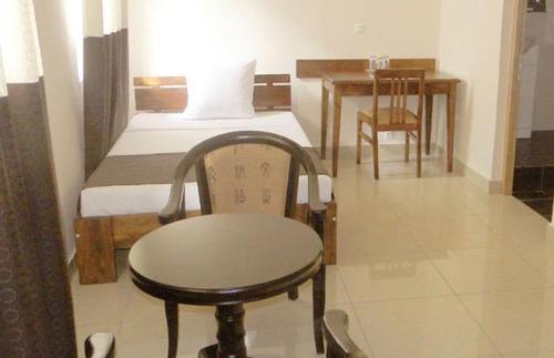 um pequeno quarto com uma cama, uma mesa e uma cadeira em Hotel H1 em Toamasina
