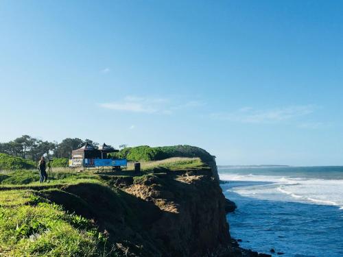 a house on top of a cliff next to the ocean at Hostel Playa Grande Austral in Mar del Plata