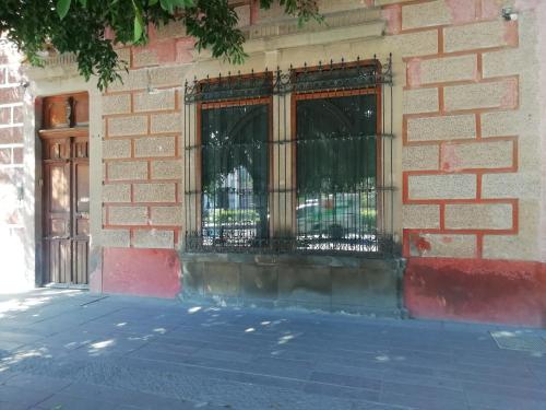 a brick building with a barred window and a door at GRAN ALCÁZAR HOTEL BOUTIQUE in San Luis Potosí