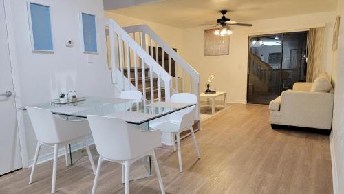 a dining room with a glass table and white chairs at Comfortable Townhome 2BR 1-5BA - Near UF & Shopping Dining in Gainesville