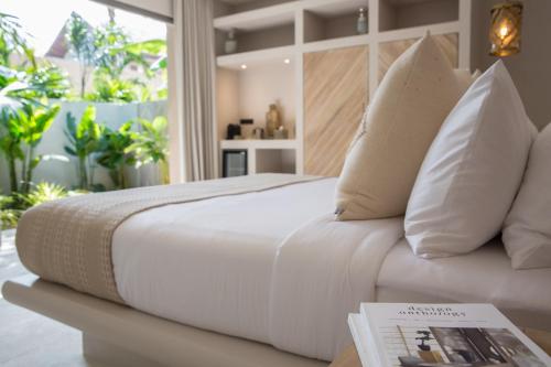 Una cama blanca con almohadas y un libro sobre una mesa. en Cielo Boutique Hotel & Spa Samui, en Bophut 