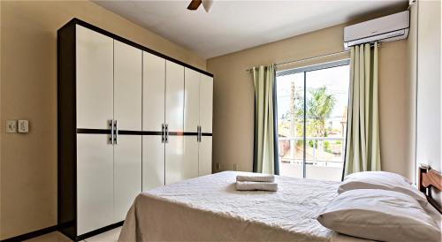 1 dormitorio con cama y ventana grande en Confortável casa duplex na Praia Santinho-Ingleses a minutos do mar e comércios - ideal para famílias, en Florianópolis