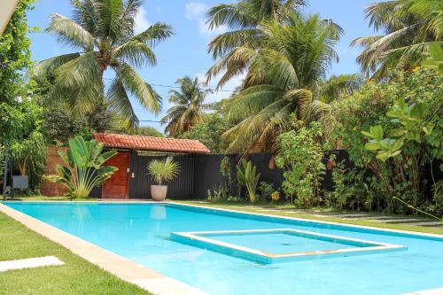 a swimming pool in the yard of a house with palm trees at Harmonia Flats in Pipa