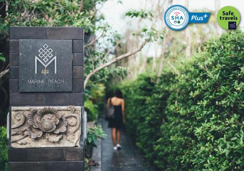 a woman walking down a path in a garden at Marine Beach Hotel Pattaya - SHA Plus in Jomtien Beach