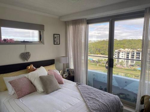 Schlafzimmer mit einem Bett und einem großen Fenster in der Unterkunft Alex Beachfront 3 brm Apartment - 9th floor in Alexandra Headland