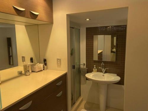 ein Bad mit einem Waschbecken und einem Spiegel in der Unterkunft Alex Beachfront 3 brm Apartment - 9th floor in Alexandra Headland