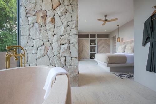 a bedroom with a stone wall and a bed and a tub at Cielo Boutique Hotel & Spa Samui in Bophut 