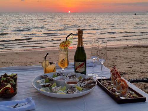 a table with a plate of food and wine on the beach at Sahaa Beach Resort in Sihanoukville