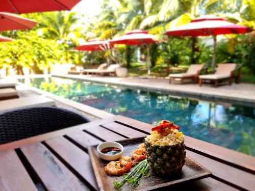 a pineapple and shrimp on a table next to a pool at Sahaa Beach Resort in Sihanoukville