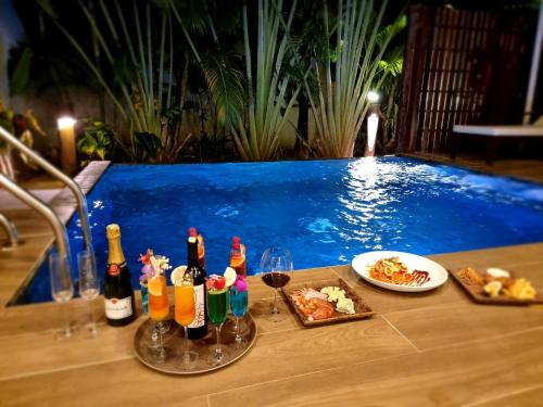 a table with drinks and food next to a swimming pool at Sahaa Beach Resort in Sihanoukville