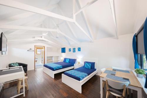 a living room with two beds and a table at Airlie Beach Magnums - Adults Only in Airlie Beach