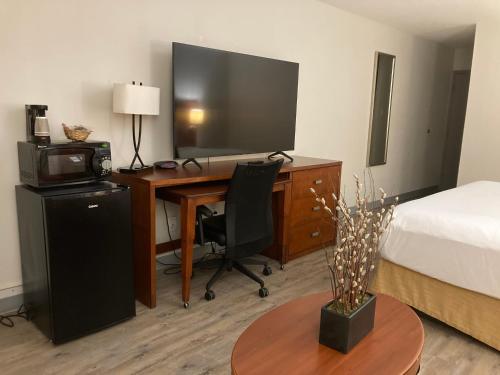 a hotel room with a desk with a bed and a television at The Hotel Orange in Orange