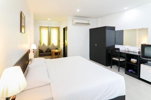 a hotel room with a white bed and a desk at G House Hotel in Hua Hin