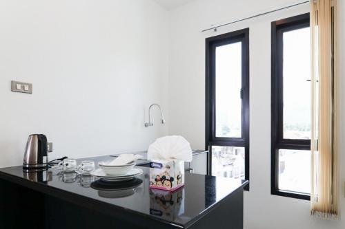 a kitchen with a black counter top with two windows at G House Hotel in Hua Hin