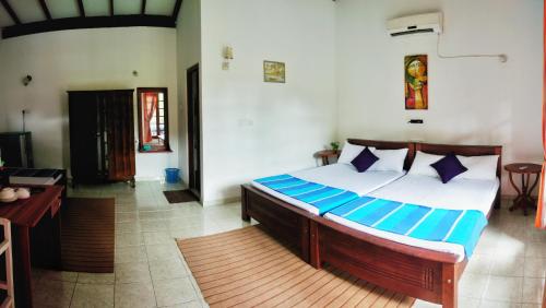 a bedroom with a large bed with blue pillows at DANDELION - Unawatuna in Unawatuna