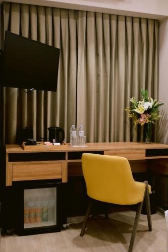 a desk with a yellow chair and a television at Goldberry Suites and Hotel Cebu in Cebu City
