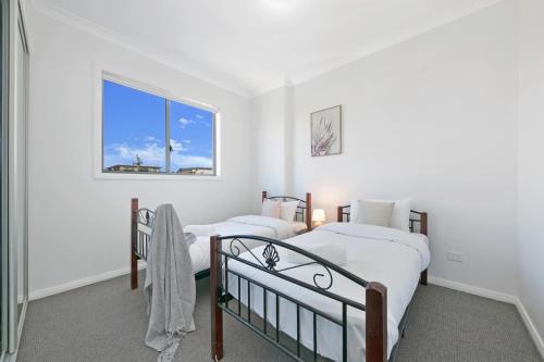 two beds in a room with a window at KOZYGURU WENTWORTHVILLE KOZY 2 BED 1 BATH APT STREET PARKING NWE049 in Wentworthville