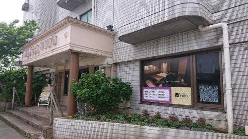una tienda frente a un edificio con un cartel en la ventana en Hotel VINO Adult Only, en Kawaguchi