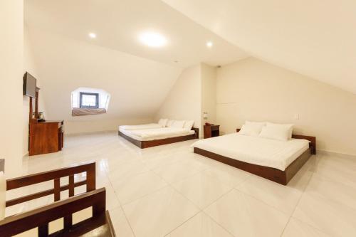 a bedroom with two beds and a tv in it at Bonjour Da Lat Hotel in Da Lat