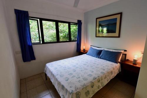 a bedroom with a bed and two windows at Thornton Beach Bungalows Daintree in Cape Tribulation