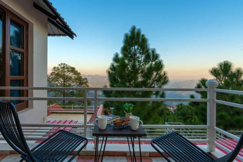 a table and chairs on a balcony with a view at StayVista at The Haven in Kasauli