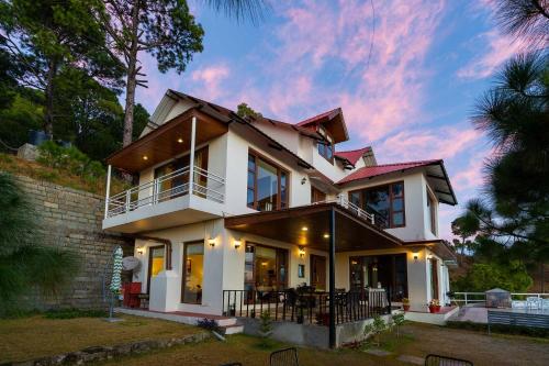 a house with a sunset in the background at StayVista at The Haven in Kasauli