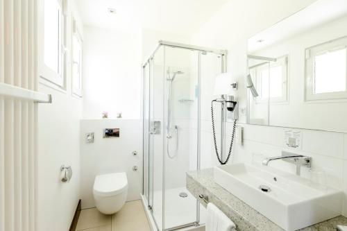a white bathroom with a sink and a shower at Seminar- & Tagungshotel Große Ledder in Wermelskirchen