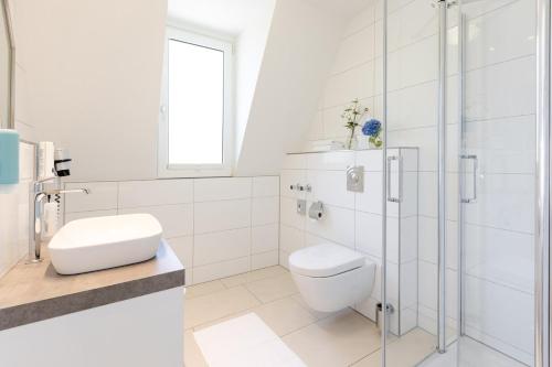 a white bathroom with a toilet and a shower at Seminar- & Tagungshotel Große Ledder in Wermelskirchen