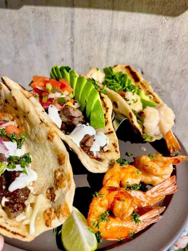 three tacos with shrimp and vegetables on a plate at Blue Entrance in Onna