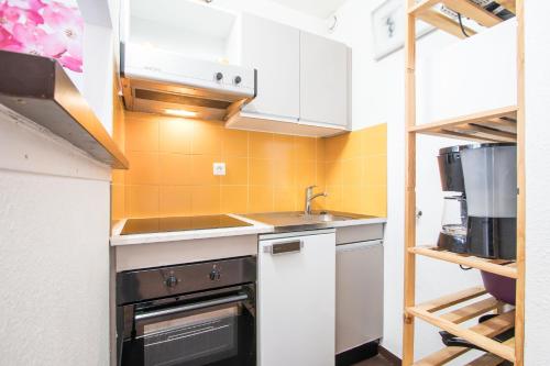 une petite cuisine avec des armoires blanches et un évier dans l'établissement Plaza Valberg centre studio cabine, à Valberg