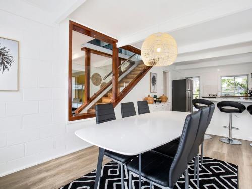 a white dining room with a white table and black chairs at Sunfish Pet Friendly 4 Mins Walk to Beach in Culburra Beach