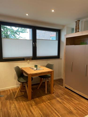 a kitchen with a wooden table and chairs and two windows at City-Apparte ONE Zentrales & komfortables Wohnen in Gronau in Gronau
