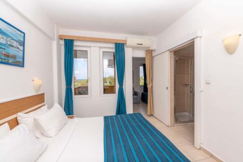 a bedroom with a bed with blue curtains and a window at Armas Green Fugla Beach in Avsallar