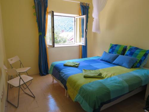ein Schlafzimmer mit einem Bett, einem Fenster und einem Stuhl in der Unterkunft Prime and Exclusive Seafront Location Apartment Sunset in Trpanj