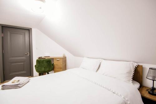 a bedroom with a white bed and a green chair at Roua Bucovinei in Sadova