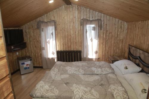 a bedroom with a bed and a tv and windows at Fish Hotel in Akhalk'alak'i