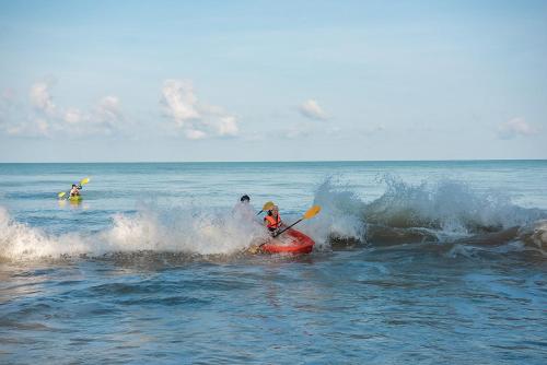a group of people riding a wave in the ocean at The Haven Khao Lak in Khao Lak