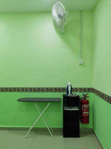 a green and white room with a table and a fire extinguisher at TAMU KoGURU in Jertih
