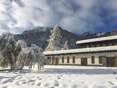 a building covered in snow with mountains in the background at Gressoney Saint-Jean apartments by Halldis in Gressoney-Saint-Jean