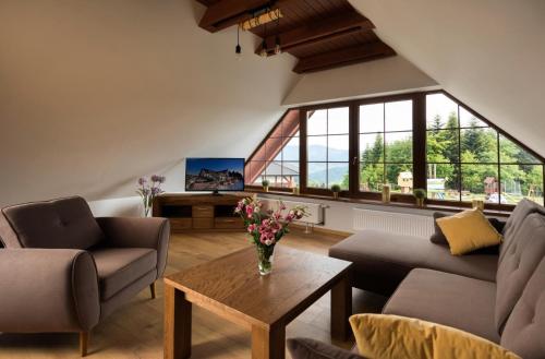 a living room with two couches and a table with flowers on it at Hotel Beskidzki Raj Medical SPA in Stryszawa
