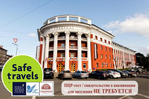 un gran edificio con coches estacionados frente a él en Severnaya Hotel, en Petrozavodsk