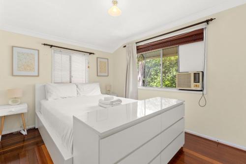 a white bedroom with a large white bed and a window at KOZYGURU ALBION CHARMING HOUSE WITH 3 BEDROOM PARKING -QAL035 in Brisbane