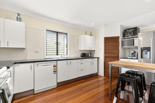 a kitchen with white cabinets and a wooden floor at KOZYGURU ALBION CHARMING HOUSE WITH 3 BEDROOM PARKING -QAL035 in Brisbane