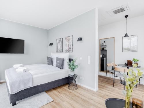 a white bedroom with a bed and a dining room at Limehome Mönchengladbach Fliethstraße in Mönchengladbach