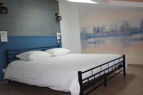 a bed with white sheets and pillows in a room at Logement de La Sittelle in Aizenay