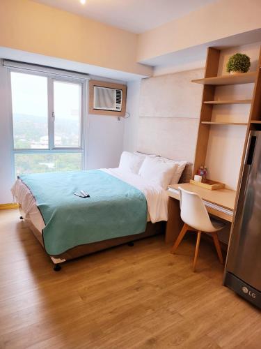 a bedroom with a bed and a desk and a television at Steff's Condo 1805 at Centrio Tower in Cagayan de Oro