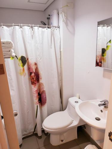 a bathroom with a shower curtain with a toilet and a sink at Steff's Condo 1805 at Centrio Tower in Cagayan de Oro