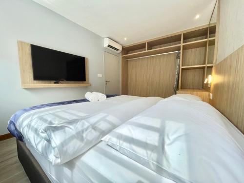 a bedroom with two white beds and a flat screen tv at LV Modern Suite Langkawi by Zervin in Kuah