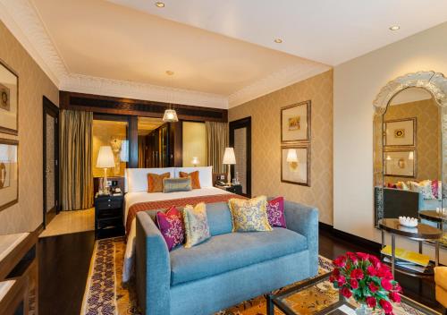 a hotel room with a bed and a blue couch at The Leela Palace Udaipur in Udaipur