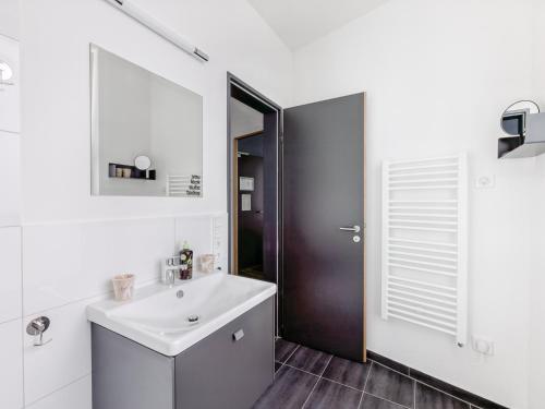 a white bathroom with a sink and a mirror at Limehome Mönchengladbach Fliethstraße in Mönchengladbach